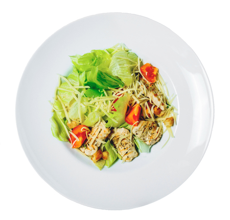 Caesar salad with Romaine lettuce, tomatoes, grilled chicken, croutons and cheese on a plate. Isolated on white background.の写真素材