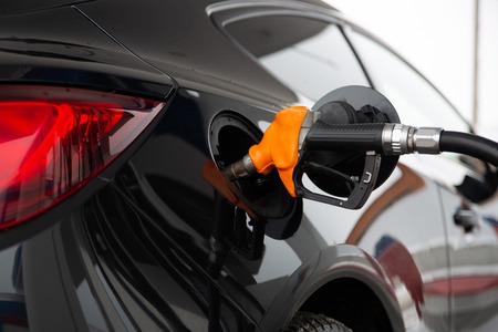 Black new car refuels at the gas station. Gun in the gas-tank.