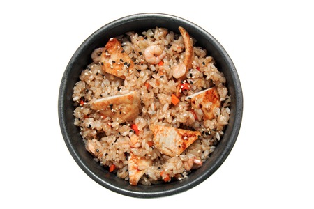 Rice with fried chicken, shrimps, vegetables and sesame in the black bowl. Isolated on white background. Tasty restaurant dish.の写真素材