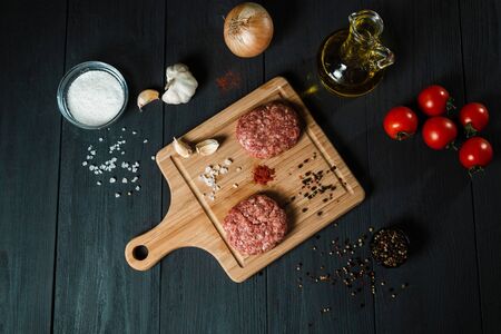 Cutlets from minced meat with the ingredients on the black wooden table. Home cooking.の写真素材