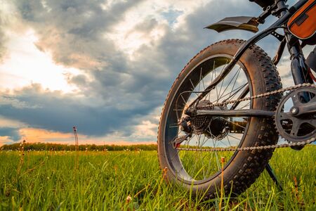 A Bicycle with thick wheels equipped with an electric motor. Fatbike against a beautiful sky.