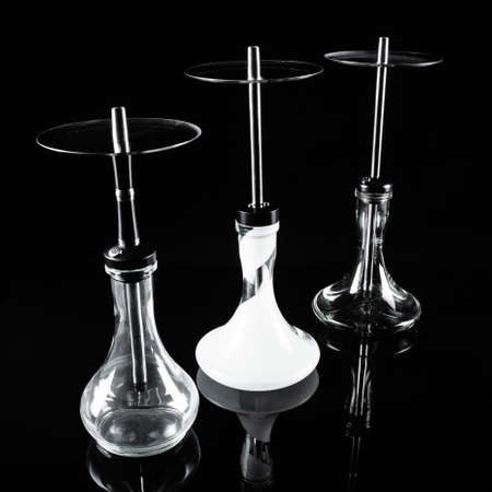 Three hookahs on a black background with a reflection.