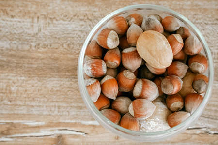 Hazelnuts in a glass cup on a wooden background. A rich source of vegetable fats.の写真素材