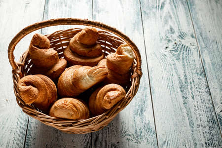 Croissants in a wicker basket on a wooden background with a copy of the space. Old white and blue boards.の写真素材