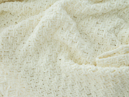 Background of white knitted plaid. Creases on soft surfaces.