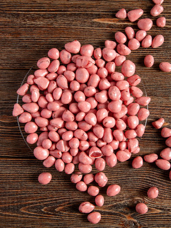 Pink candies on a brown wooden background. Candies with filling in a glass plate.