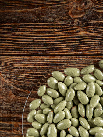 Green chocolates on a brown wooden background. Sweets in a glass plate.の写真素材