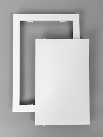 White plastic hatch on a gray background. Rectangular shape. Door for access to the pipes.の写真素材