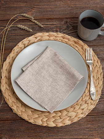 Beige napkin on a plate. Serving on a brown wooden table.の写真素材