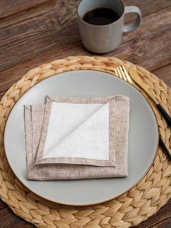 Beige napkin on a plate. Serving on a brown wooden table.の写真素材