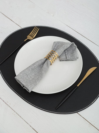 Gray napkin on a white plate. Serving on wooden table.の写真素材