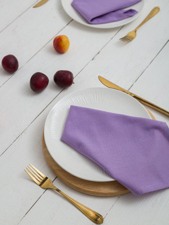 Purple napkin on a white plate. Serving on wooden table.の写真素材