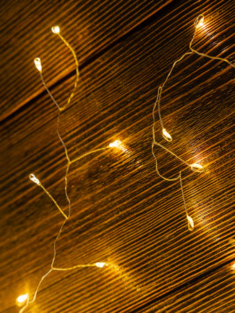 Garland glows yellow on a brown wooden background. Close-up.の写真素材