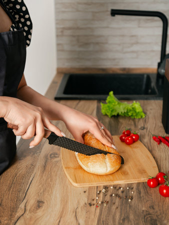 Girl cuts bread on a wooden board with a knife. Location of the kitchen.