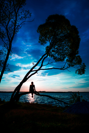 Silhouette of woman and tree at sunsetの写真素材