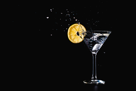 Cocktail water drink splash in the glass with lemon Isolated on black background