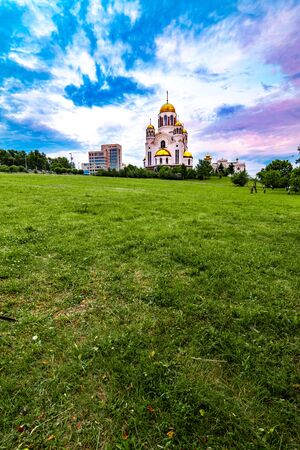 Wide angled view of the church Temple On The Blood in Yekaterinburg, Russia with beautiful cloudy sky and green grass on the foregroundの写真素材