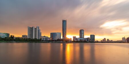 Beautiful cloudy sunset at the city pond. Long Exposure cityscape of Yekaterinburg, Russia with skyscrappers reflecting in waterの写真素材
