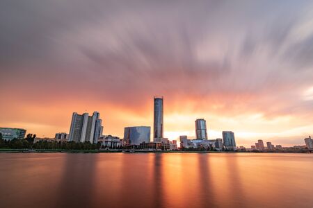 Beautiful cloudy sunset at the city pond. Long Exposure cityscape of Yekaterinburg, Russia with skyscrappers reflecting in waterの写真素材