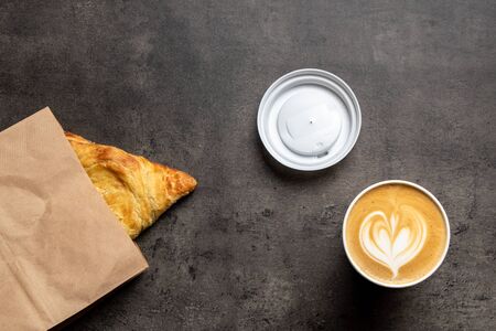 Samsa in paper envelope and cappuccino in paper cup on concrete gray background top viewの写真素材