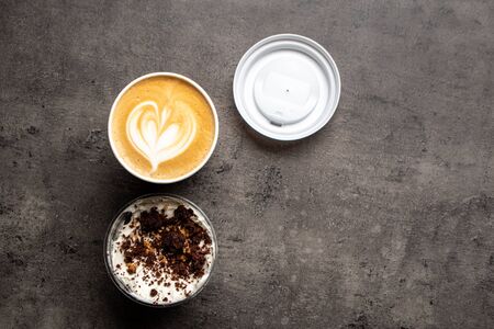 Dessert in plastic container and cup of cappuccino to go top view on grey backgroundの写真素材