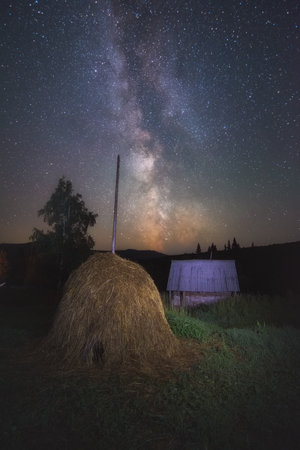 milky way and myriads of stars in a haystack on the outskirts of a village on a summer nightの写真素材