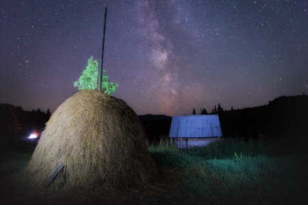 milky way and myriads of stars in a haystack on the outskirts of a village on a summer nightの写真素材
