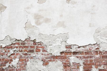Texture of an old brick wall with fallen plaster. Background of a shabby building surface.の写真素材