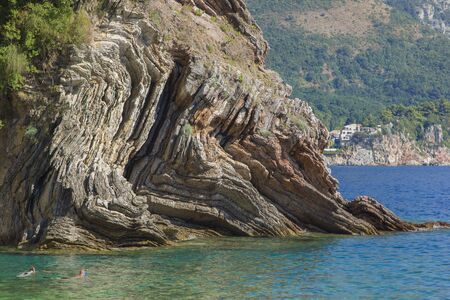 On a bright summer day, father and son are snorkeling at a high cliff, swimming and diving into the water.の写真素材