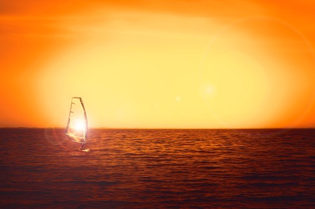 Windsurfer silhouette at sea sunset. Beautiful beach seascape. Summertime watersports activities, vacation and travel concept, backgroundの写真素材