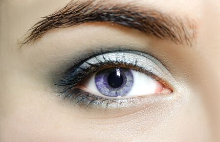 Violet eyes (mutation eyes), Close Up. The human eye of a woman with light beauty cosmetics and long natural eyelashes. Girl with perfect skin.の写真素材