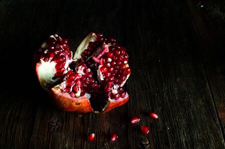 Open fresh ripe pomegranates on wooden background.の写真素材