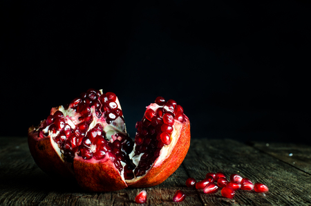 Open fresh ripe pomegranates on wooden background.の写真素材