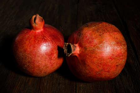 Two ripe garnet on a rustic wooden background.