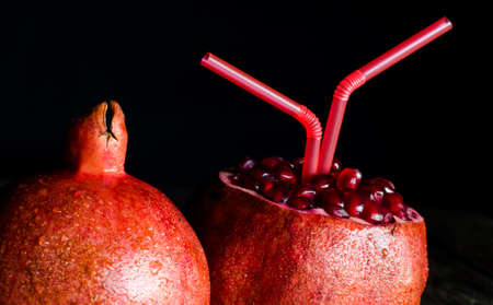 ripe garnet with drinking straw on wooden background.の写真素材