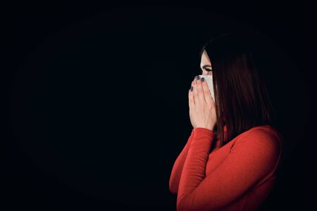 Profile image of young female wearing face mask isolated on black. Free from copy space.
