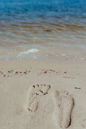 Foot prints at sand in sunrise on tropical beachの写真素材