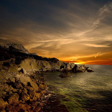 dark rock and sea coast at sunset timeの写真素材