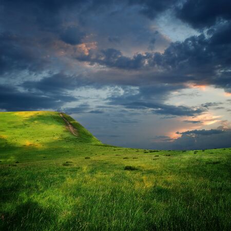 meadow and majestic sky with clouds over the green hills の写真素材