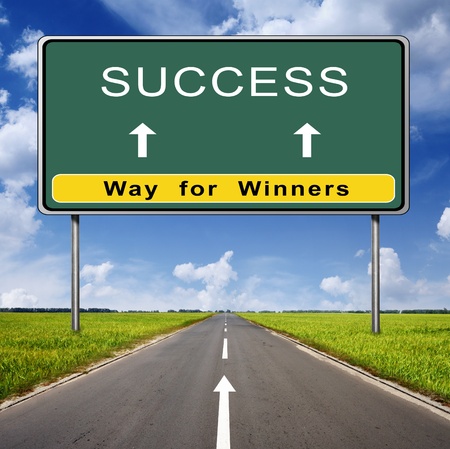 success road sign on blue sky background and green fieldの写真素材