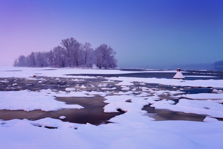 winter river with cracked ice and light after sunset in hazeの写真素材