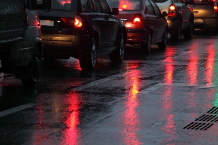 cars in traffic jam on wet road at rainy city eveningの写真素材