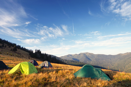 camping tents on the meadow after sunrise, mountains on backgroundの写真素材
