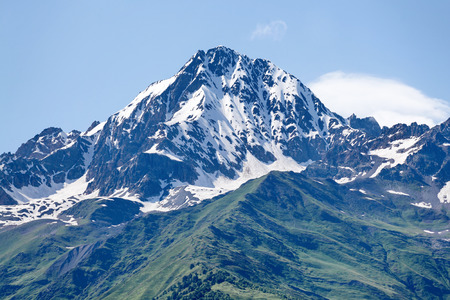 Mountain peak in snow and green hills below. Svaneti, Georgiaの写真素材