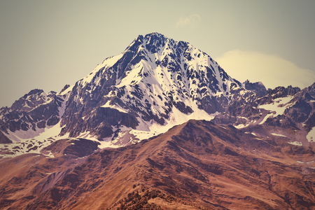 Peak in snow and brown grass below. Svaneti, Georgiaの写真素材