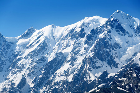 Mountain summit under snow. Winter landscape in cold sunny day. Blue sky above a peakの写真素材