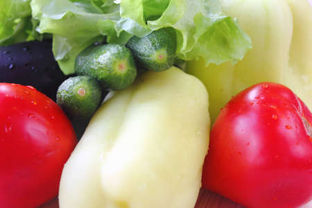 Fresh tomatoes, cucumbers, pepper, eggplant and lettuce on wood table.の写真素材