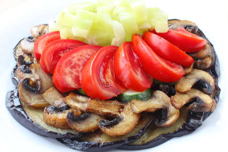 Fried eggplants and mushrooms with fresh tomatoes, cucumbers and pepper on white plateの写真素材