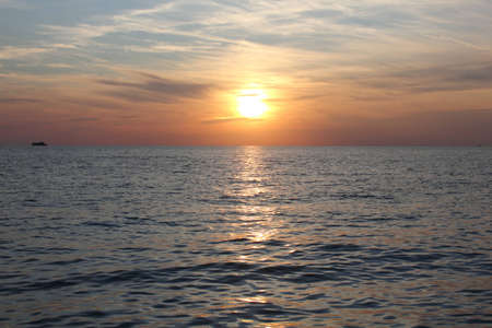 Sunset on sea with ship on horizonの写真素材