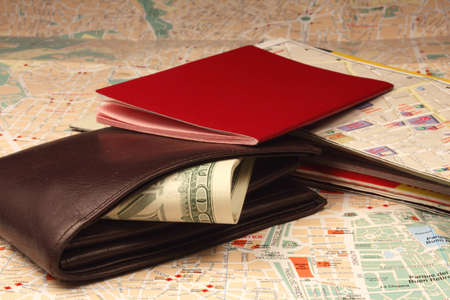 Wallet, passport and stack of maps on city map.の写真素材